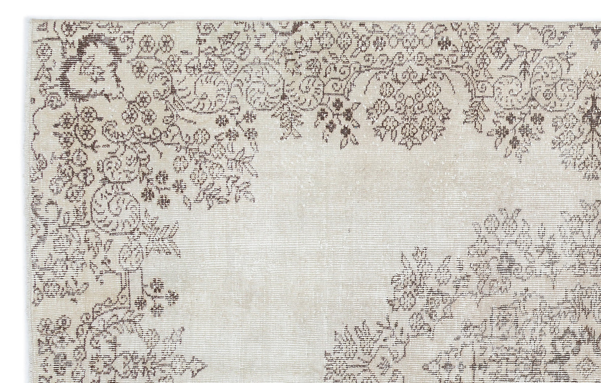 Beige and brown rug with a distressed, faded floral medallion pattern on a plain background.
