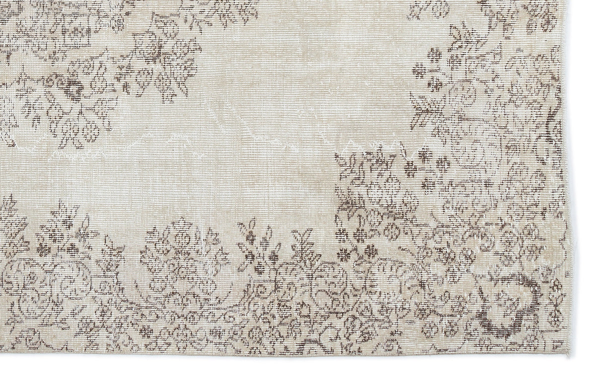 Beige rug with a distressed brown floral pattern and a faded, vintage-style texture.