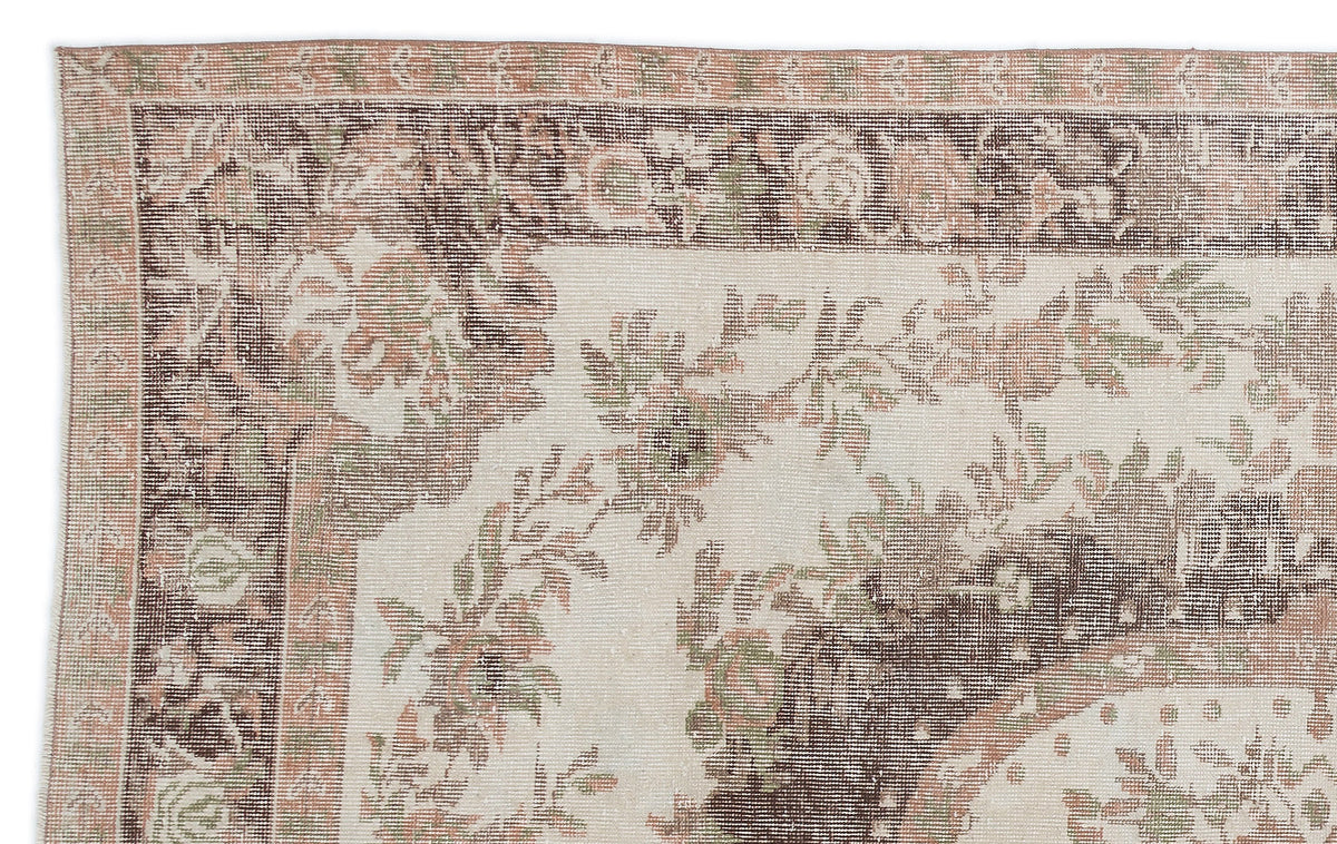 Distressed cream, brown, and muted pink rug with a traditional floral border and central medallion pattern.