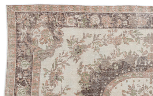 Load image 1 in gallery view. Distressed cream, brown, and muted pink rug with a traditional floral border and central medallion pattern.