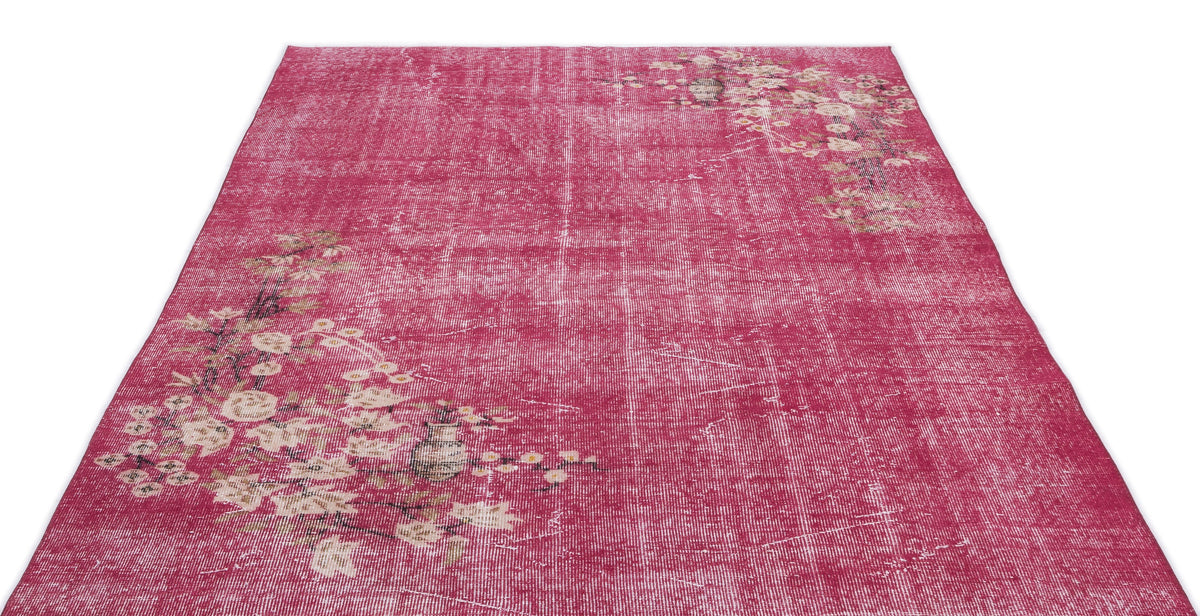 Distressed magenta rug with a faded floral pattern in cream and brown, isolated on a white background.