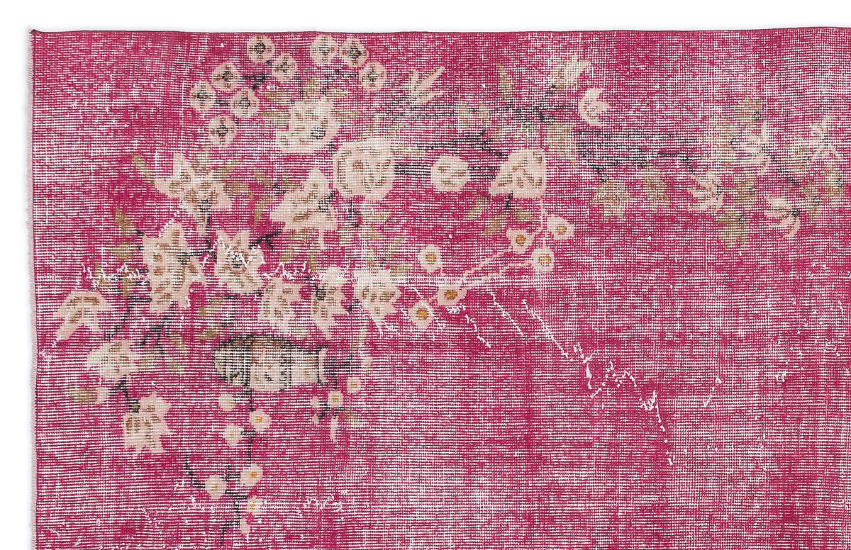 Magenta distressed rug with a faded cream and beige floral branch pattern.