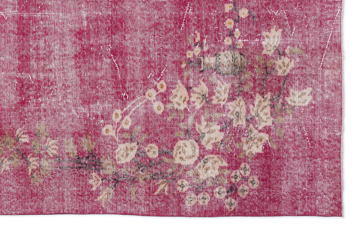 Magenta distressed rug with a faded cream floral pattern and visible woven texture.