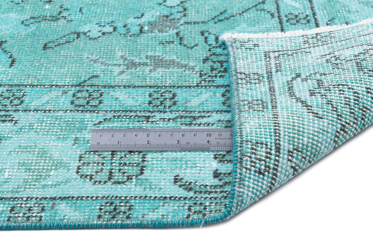 Turquoise and grey distressed rug with a traditional medallion pattern, shown with a metal ruler for scale.