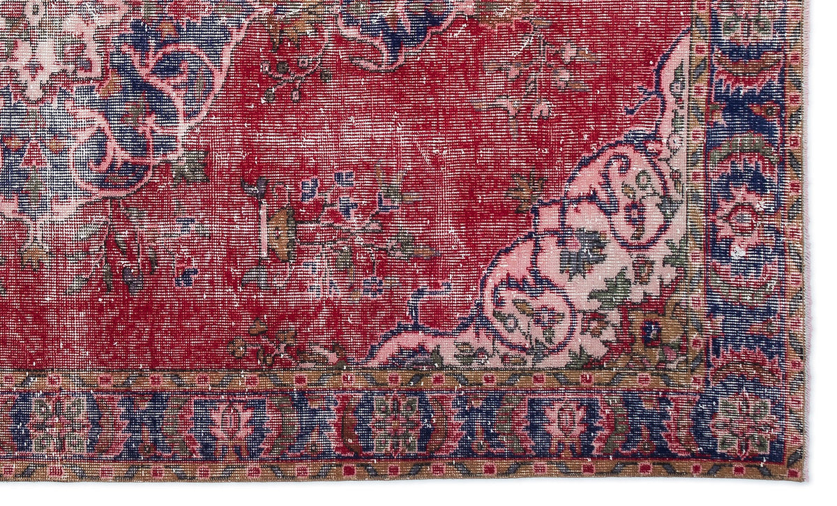 Distressed red, navy, and pink traditional rug with a floral medallion pattern and a detailed geometric border.