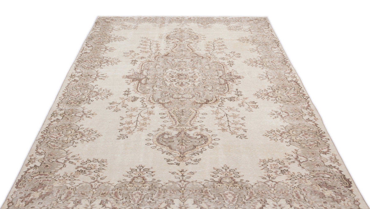 Beige and taupe distressed area rug with a traditional floral medallion pattern on a white background.
