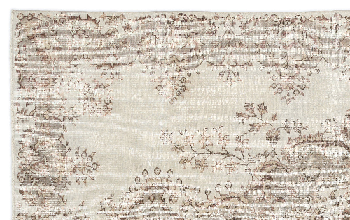 Beige and taupe vintage-style rug with a faded floral medallion pattern on a white background.