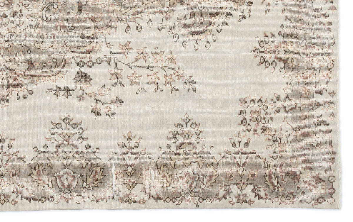 Cream and beige rug with a distressed traditional floral medallion pattern and a decorative border.