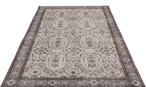 Load image 1 in gallery view. Distressed brown and cream area rug with a traditional floral medallion pattern and a wide decorative border.