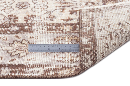Load image 1 in gallery view. Beige and brown distressed traditional rug with a floral pattern, shown with a metal ruler for scale on a white background.