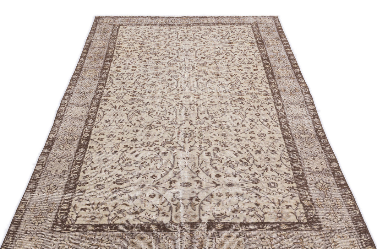 Beige and brown vintage-style rug with a distressed floral medallion pattern and a wide decorative border.