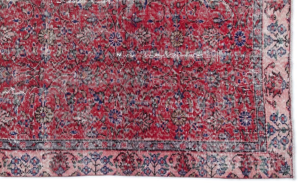 Distressed red rug with a traditional floral pattern, blue and beige accents, and a wide pink border.