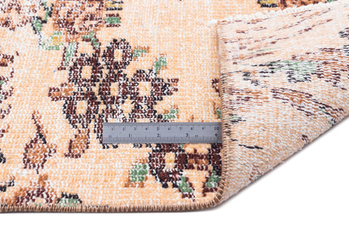 Load image 1 in gallery view. Peach, brown, and green floral patterned rug with a folded corner and a metal ruler for scale on a white background.