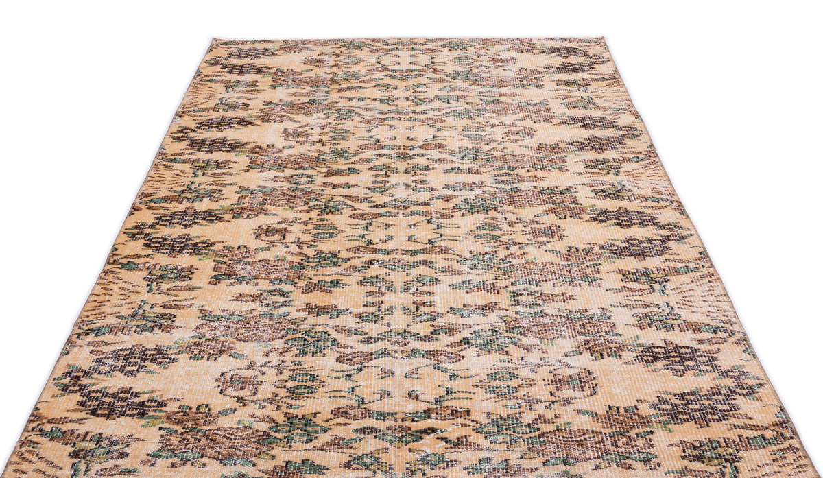 Tan vintage-style rug with a distressed, repeating floral medallion pattern in dark brown and muted green.