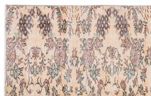 Load image 1 in gallery view. Peach-toned rug with a distressed, repeating floral medallion pattern in muted brown, green, and cream.