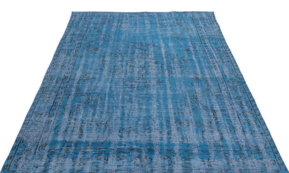 Blue distressed area rug with a faded traditional medallion pattern and dark grey border details.