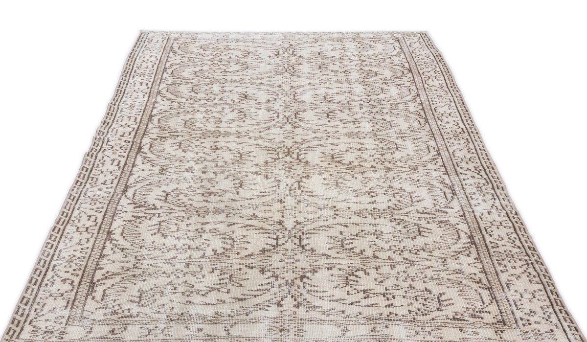 Cream and brown area rug with a distressed traditional floral medallion pattern and a decorative border.