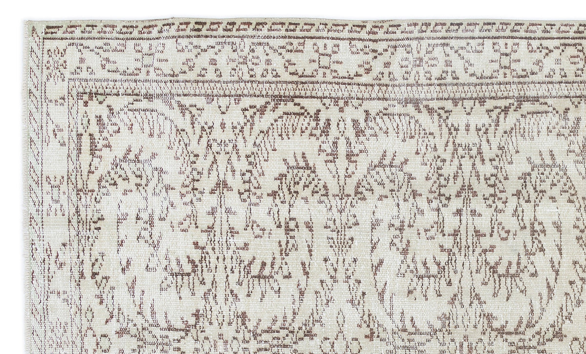 Cream and brown rug with a distressed, traditional floral medallion pattern and a detailed border.