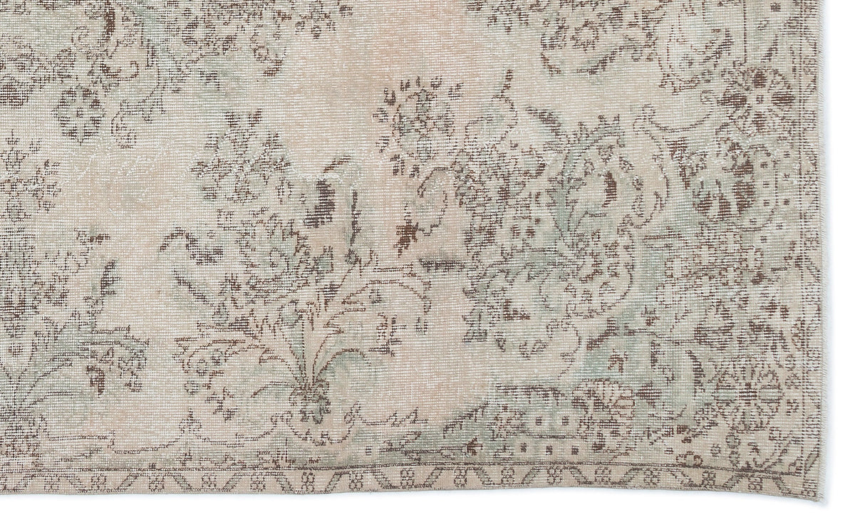 Beige and sage green vintage-style rug with a distressed floral medallion pattern.