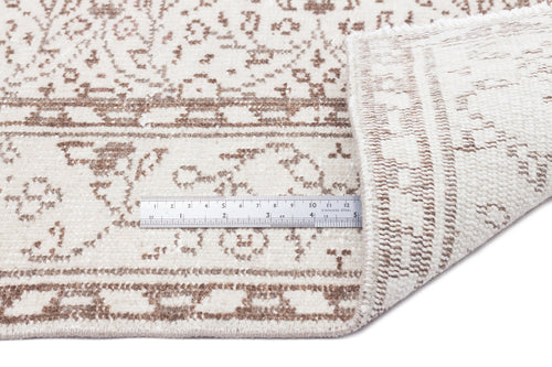 Load image 1 in gallery view. Cream and beige rug with a distressed floral pattern, shown with a metal ruler for scale on a white background.