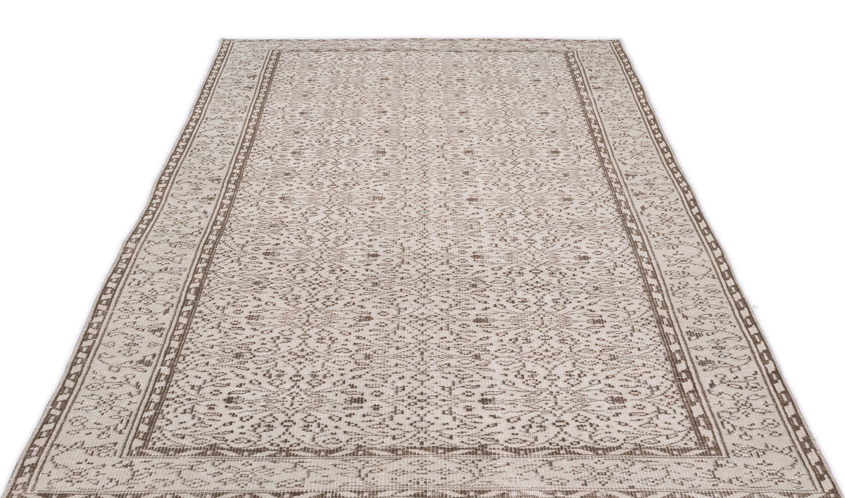Beige and brown area rug with a distressed, intricate floral medallion pattern and a geometric border.