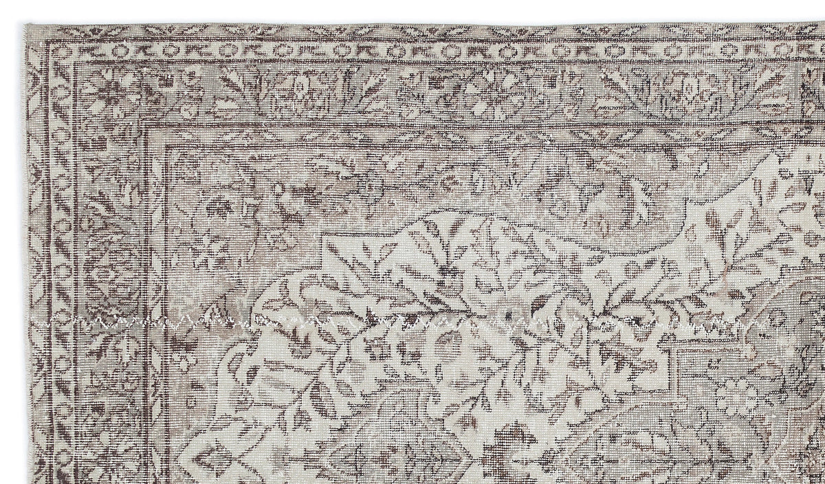 Taupe and cream vintage-style rug with a distressed floral medallion pattern and a detailed geometric border.