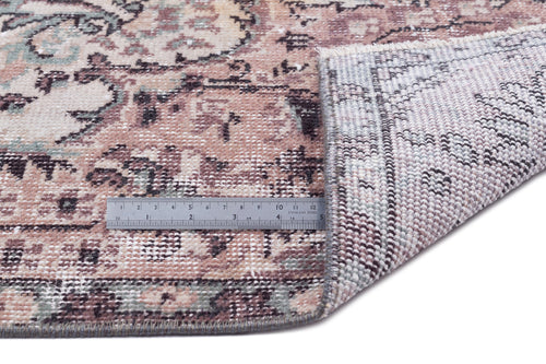 Load image 1 in gallery view. Distressed floral medallion rug in dusty rose, sage, and cream with a corner folded back to show the woven backing.