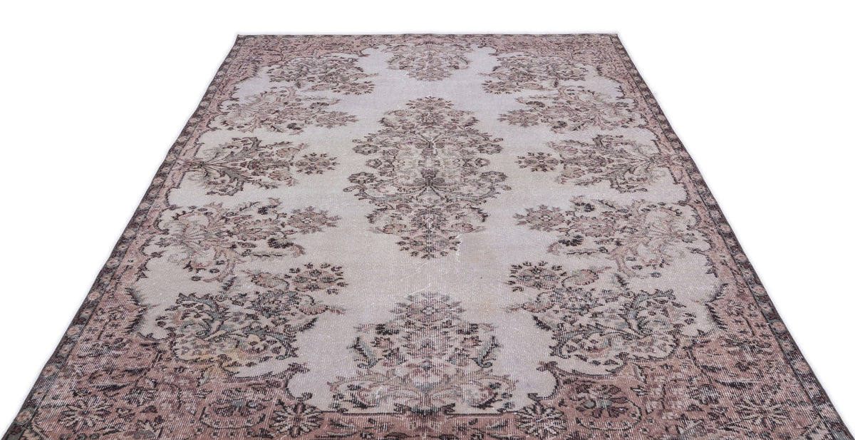 Distressed light gray rug with a faded mauve and charcoal floral medallion pattern on a white background.
