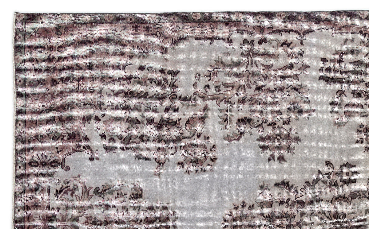 Distressed grey and mauve rug with a traditional floral medallion pattern and a decorative border.
