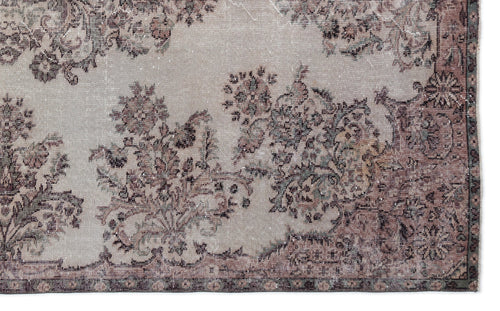 Load image 1 in gallery view. Distressed beige rug with a faded floral medallion pattern in muted brown, charcoal, and sage green tones.