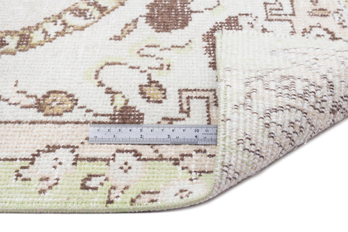 Load image 1 in gallery view. Cream, brown, and pale green rug with a traditional floral pattern, shown with a metal ruler for scale.
