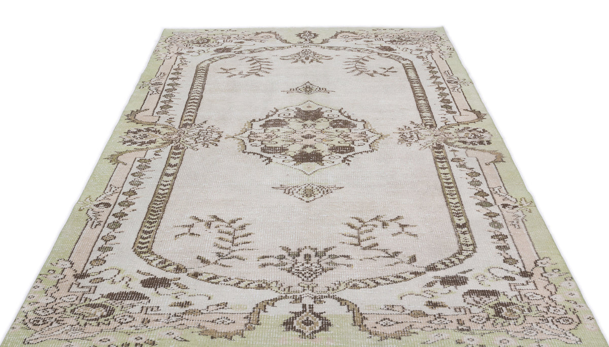 Cream and sage green vintage-style rug with a central brown floral medallion and ornate border on a white background.