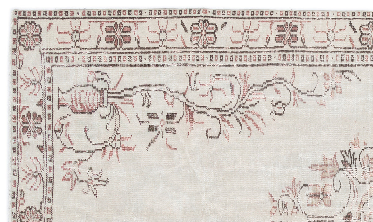 Cream rug with a faded brown and terracotta floral border and stylized botanical motifs on a white background.