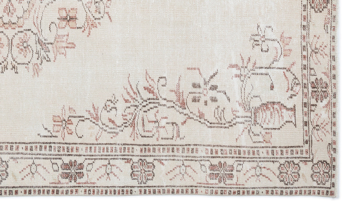 Beige rug with a faded floral medallion pattern in muted brown and terracotta, featuring a detailed geometric border.
