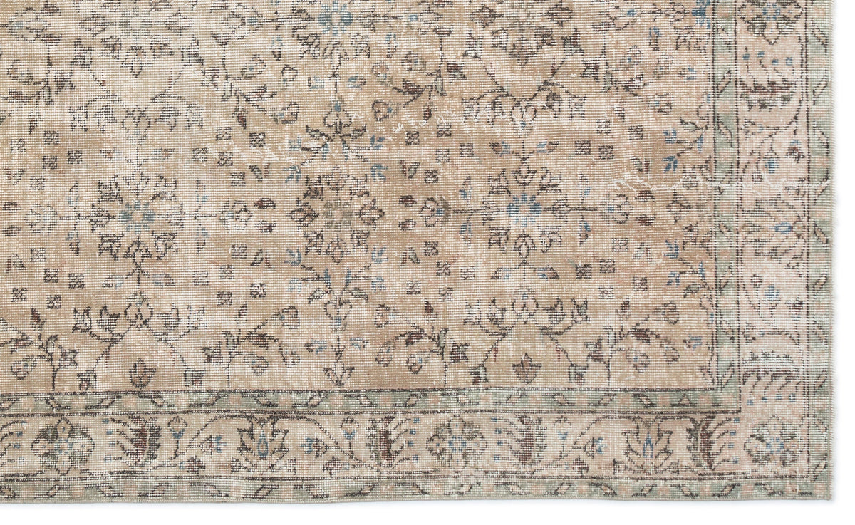 Tan rug with a distressed floral medallion pattern in blue and brown, featuring a decorative border.