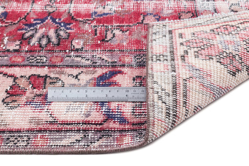 Load image 1 in gallery view. Distressed red, pink, and navy floral medallion rug with a folded corner and a metal ruler for scale.