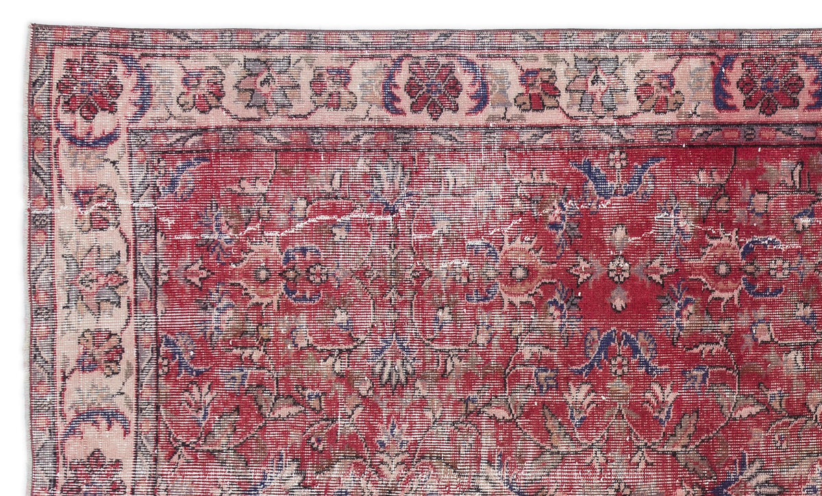 Distressed red Persian-style rug with a floral medallion pattern and a cream border featuring blue and red floral motifs.