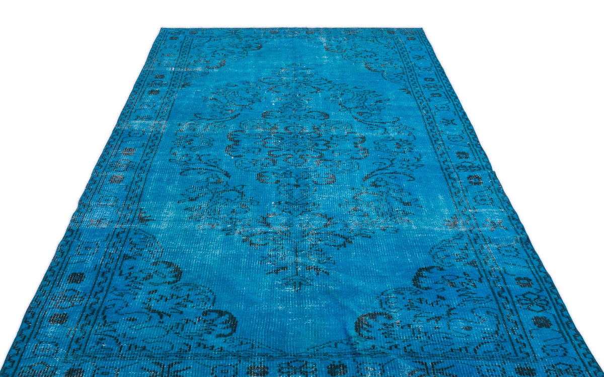 Bright blue vintage-style rug with a distressed black floral medallion pattern and ornate border.