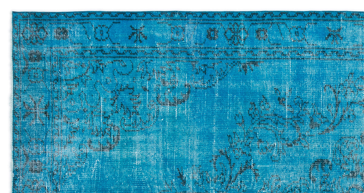 Bright blue distressed rug with a dark charcoal traditional floral medallion pattern and geometric border.