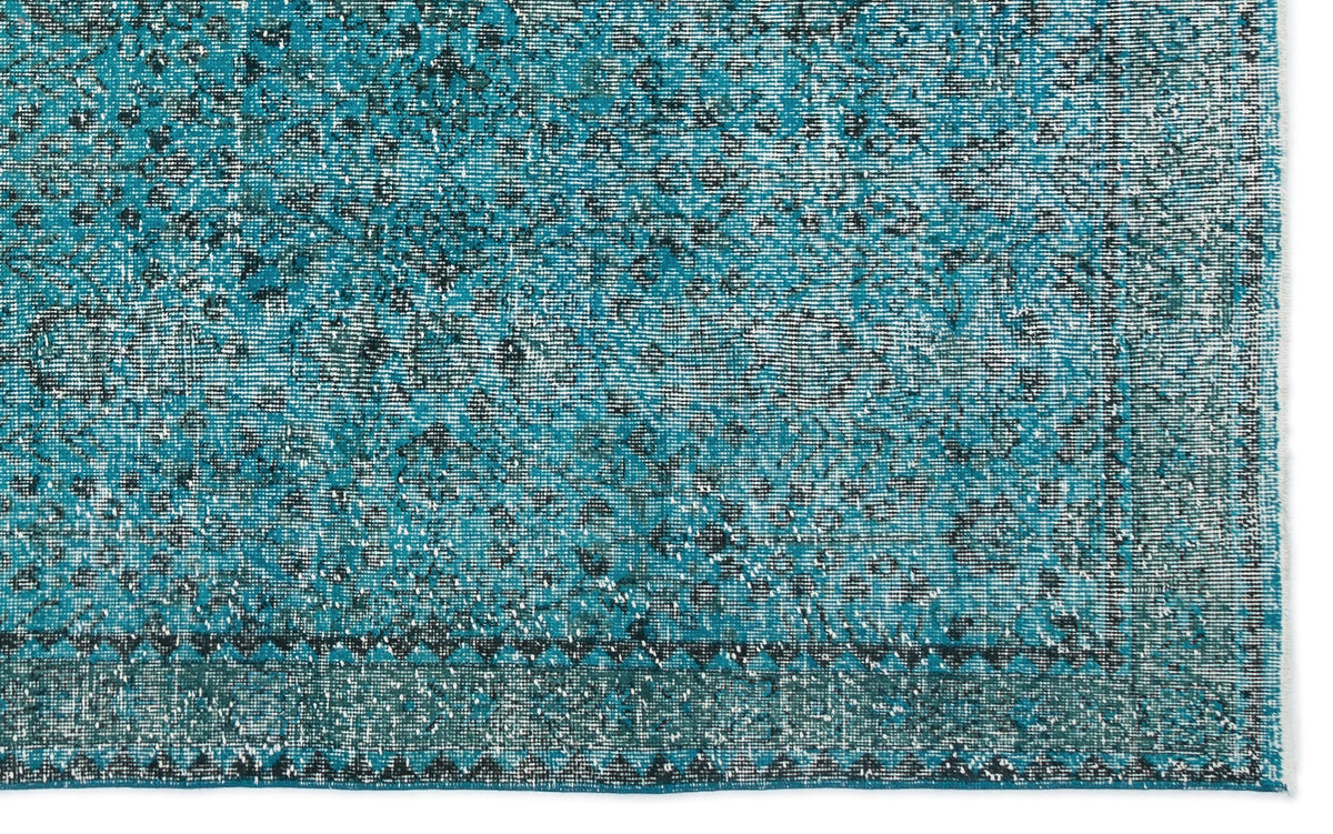 Teal and black distressed vintage-style rug with a faded floral medallion pattern and a geometric border.