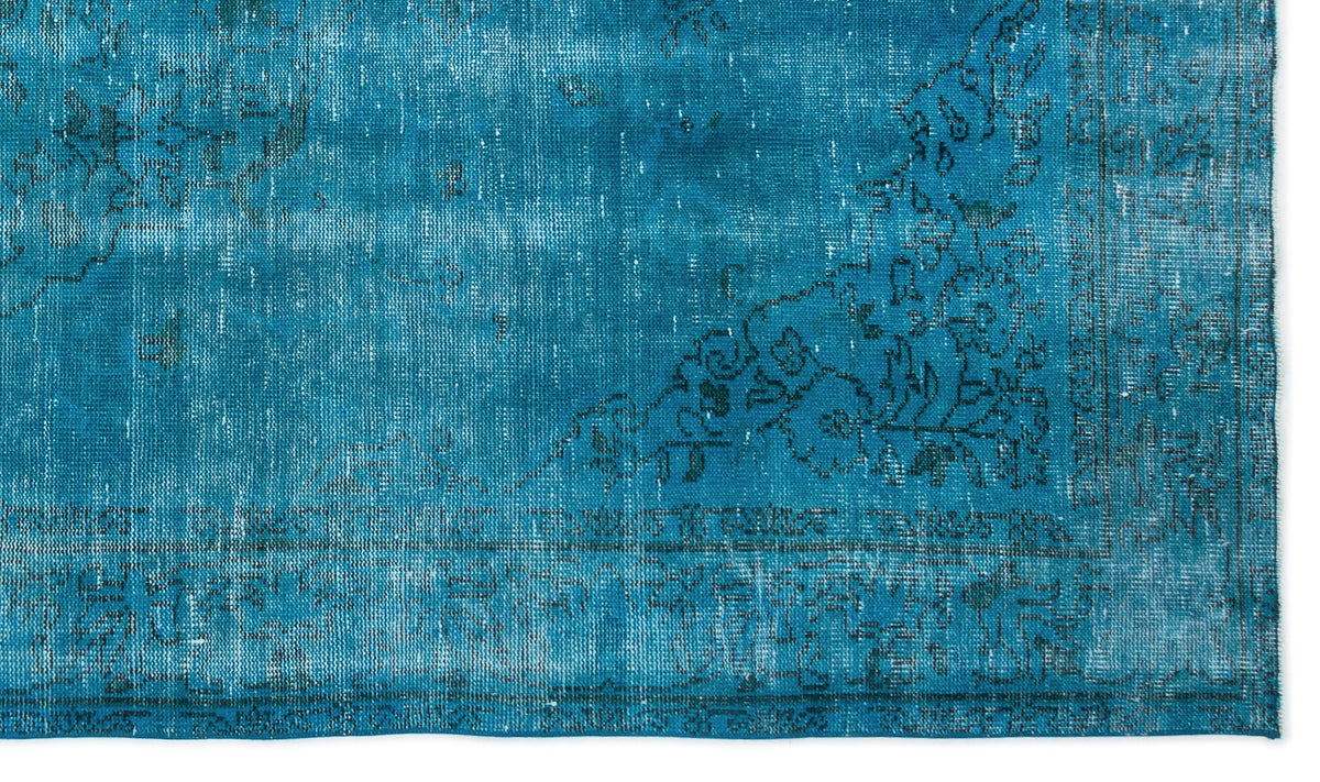 Teal distressed rug with a faded black floral medallion pattern and a decorative border.