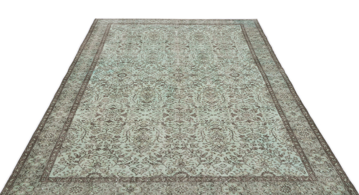 Mint green and brown distressed area rug with a traditional floral medallion pattern and a wide decorative border.