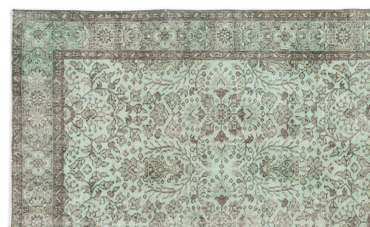 Distressed mint green and brown rug with a traditional floral medallion pattern and a decorative border.