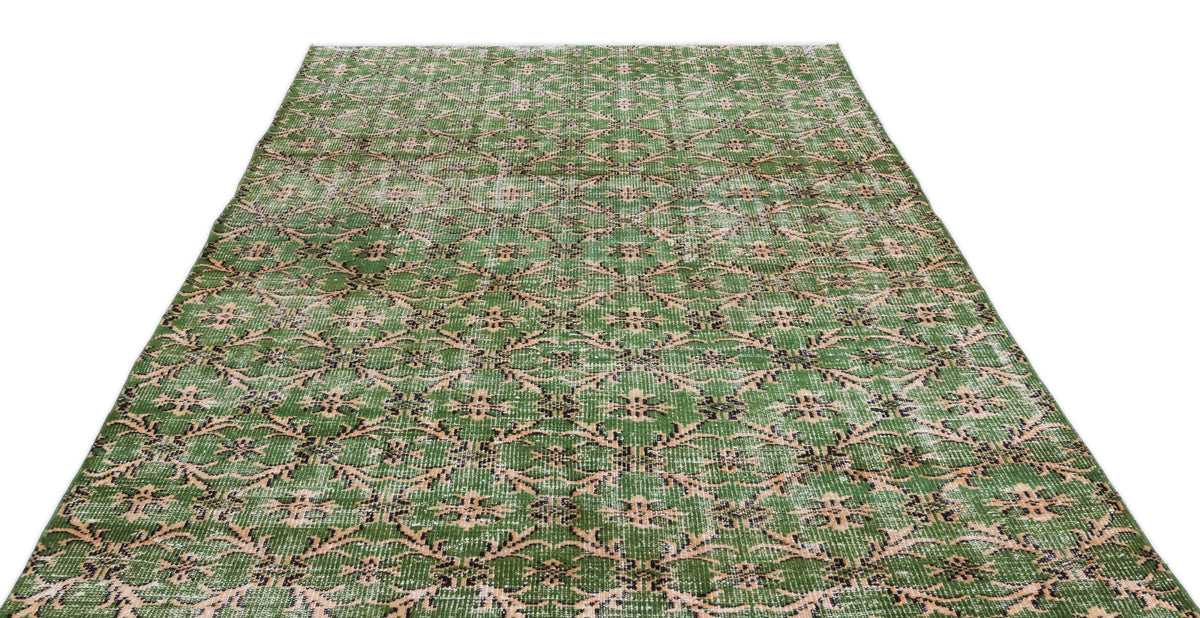 Green and beige distressed rug with a repeating geometric floral medallion pattern on a white background.