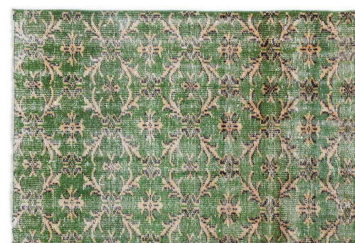 Load image 1 in gallery view. Green rug with a distressed, repeating beige and black floral medallion pattern on a white background.