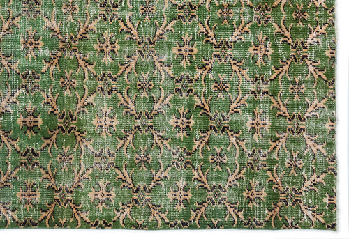 Load image 1 in gallery view. Green rug with a distressed, repeating floral medallion pattern in black and beige.