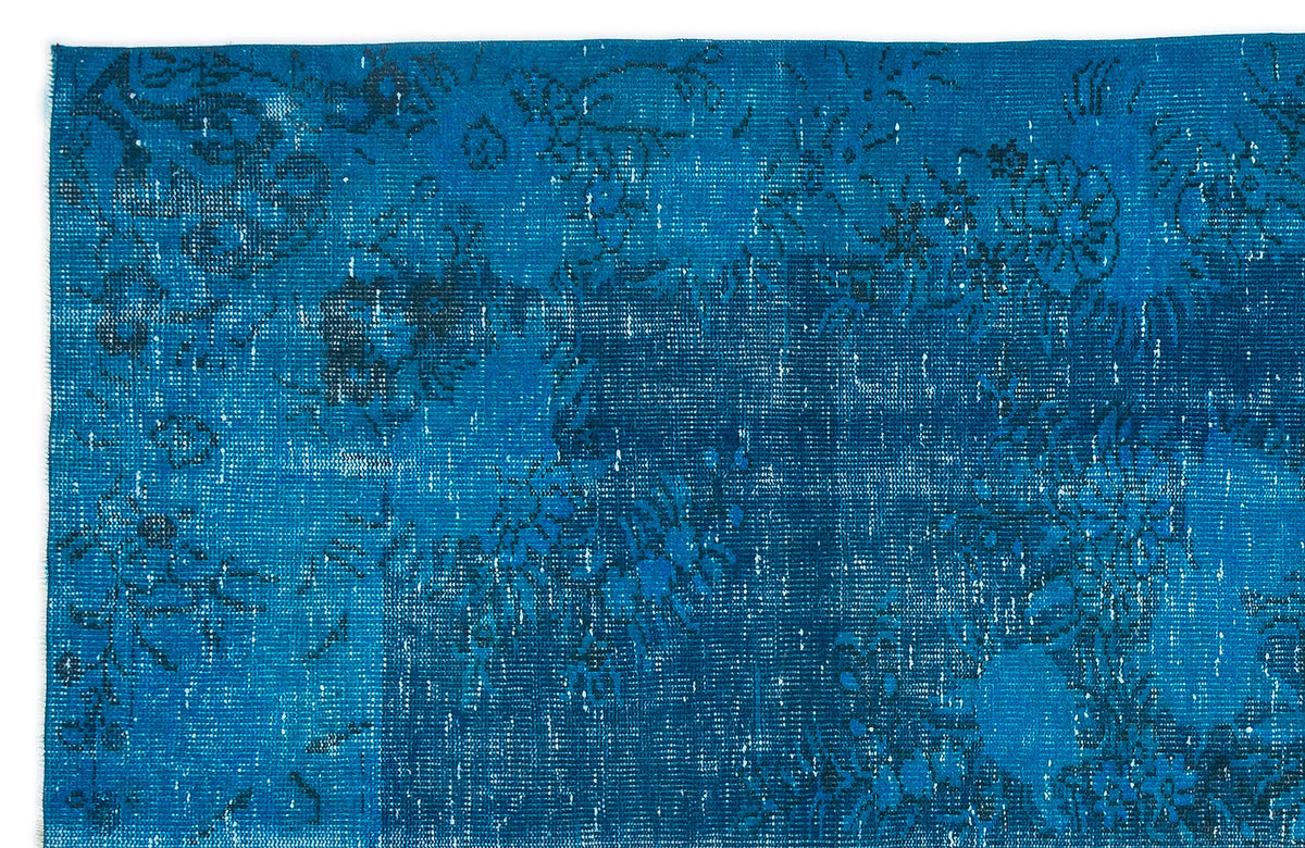 Bright blue distressed rug with a faded black floral medallion pattern.
