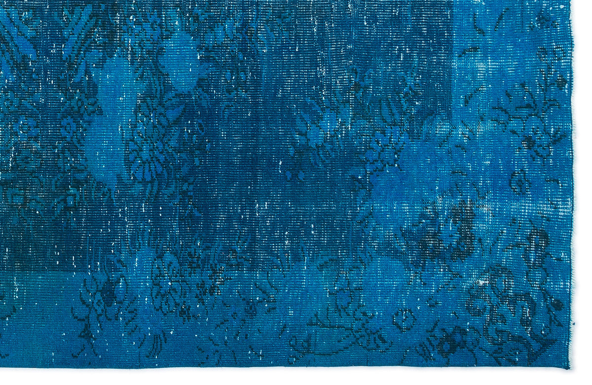 Deep blue distressed rug with a faded floral pattern and visible woven texture.