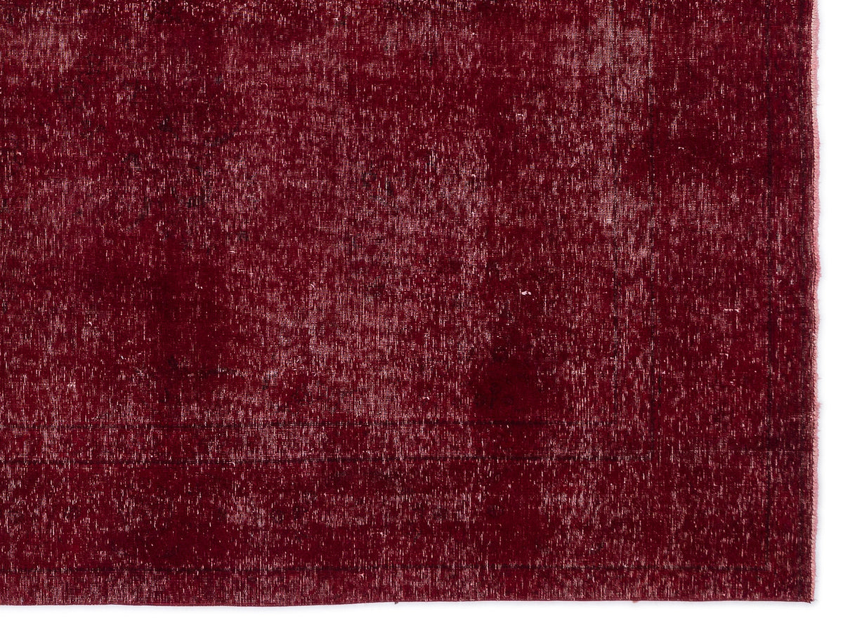 Deep red vintage-style rug with a distressed, faded texture and subtle border detail.