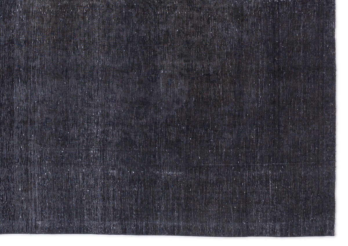 Solid charcoal black rug with a distressed, weathered texture and visible woven fiber details.